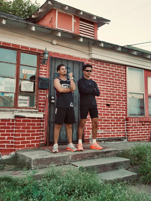 Two community members standing outside a red brick storefront